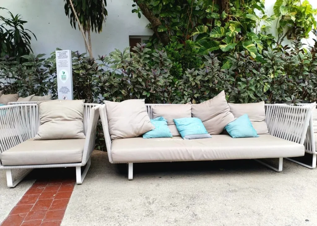 sofa con colchones azules y grises con arbustos verdes en la parte detrás